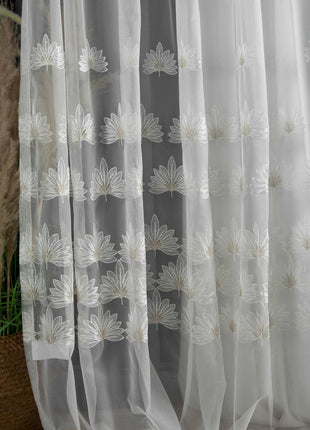 a close up of a curtain with a plant in the background