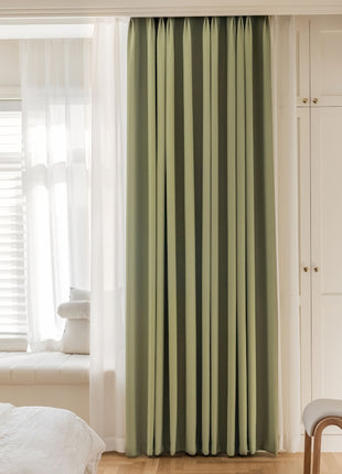 a bedroom with a white bed and green curtains