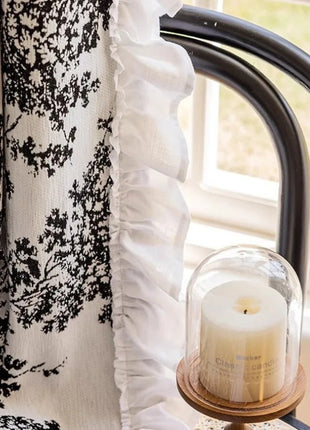 a white candle sitting on top of a table next to a window