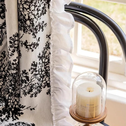 a white candle sitting on top of a table next to a window