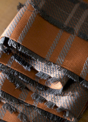 a close up of a plaid cloth with fringes