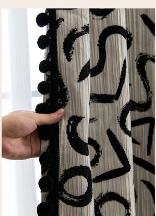 a hand holding a curtain with black and white designs