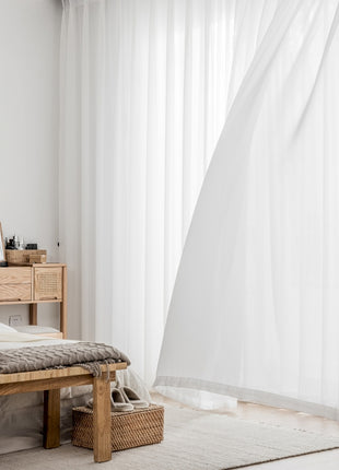 a room with a bed and a white curtain
