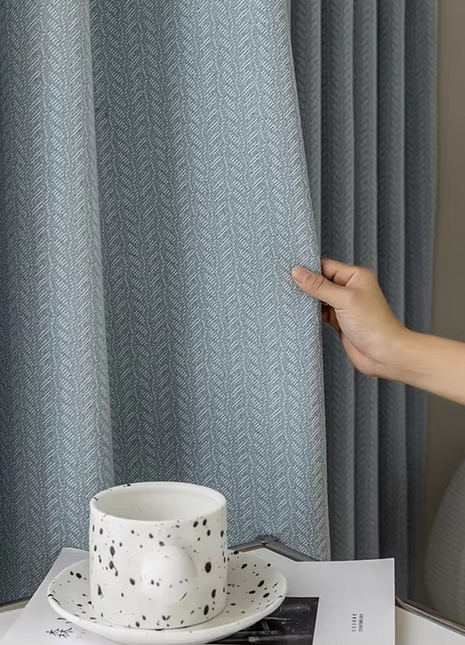 a person is holding a coffee cup in front of a curtain