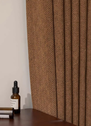 a brown curtain and a brown bottle on a wooden surface.