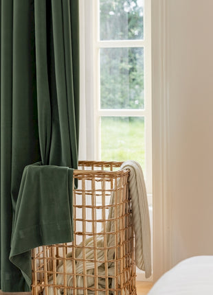 a window with a green curtain and a basket in front of it