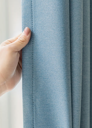 a hand is holding the curtain in front of a window