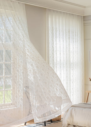 a bedroom with a bed and a white curtain