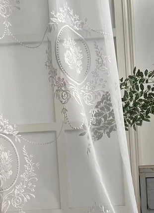 a white curtain with a floral design on it