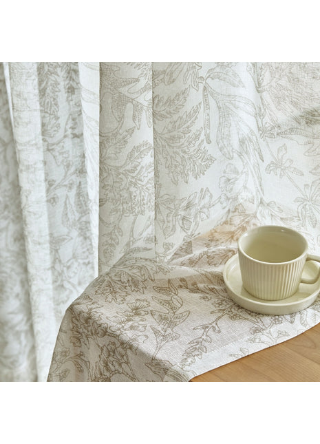a cup and saucer on a table next to a curtain