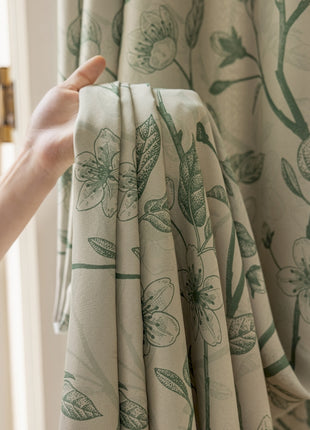 a hand is holding a curtain with a flower pattern