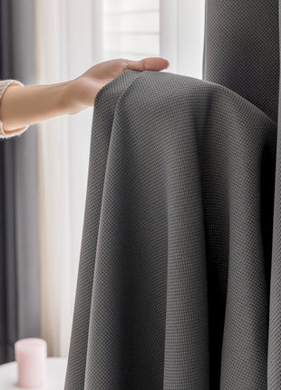 a person holding a curtain in front of a window