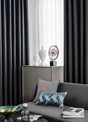 a living room with a gray couch and black curtains
