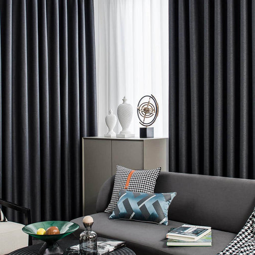 a living room with a gray couch and black curtains