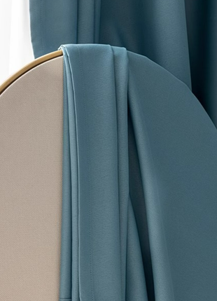 A close-up view of a light blue fabric draped over a light beige fabric, creating a soft and flowing appearance.