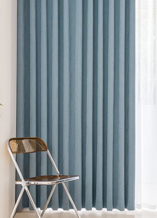 a chair sitting in front of a window with a blue curtain