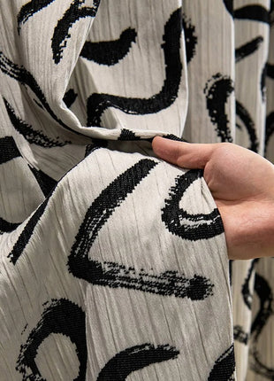 a hand holding a piece of fabric with black and white designs on it