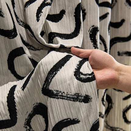 a hand holding a piece of fabric with black and white designs on it