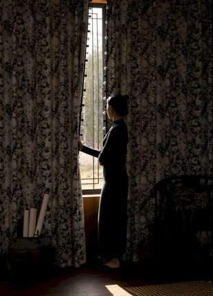 a woman standing in front of a window looking out