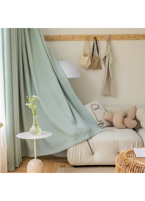 a living room with a white couch and a green curtain
