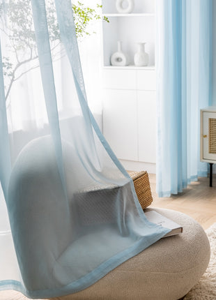 a living room with a white chair and a blue curtain