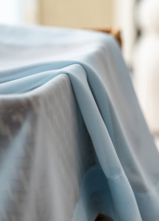 a bed covered with a blue sheet and a white chair