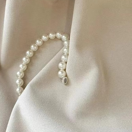 a close up of a white fabric with pearls