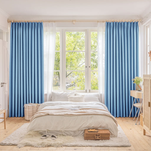 a bedroom with blue curtains and a white bed