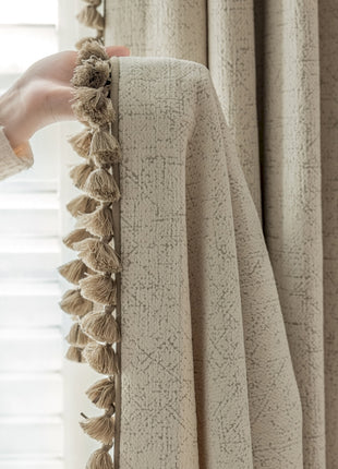 a person is holding a curtain with a tassel