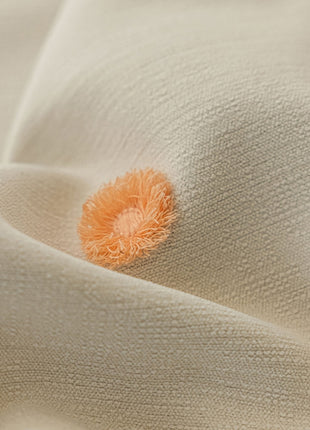 an orange pom pom on a white fabric