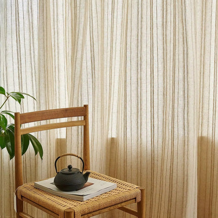 a tea pot on a chair in front of a curtain