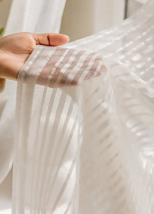 a person's hand holding a white curtain in front of a window