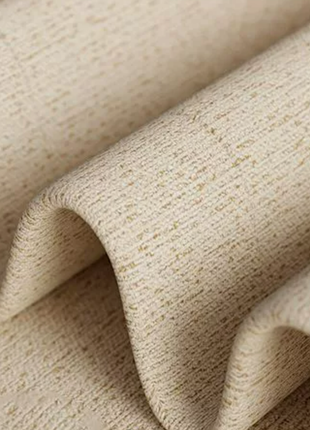 A close-up view of a textured fabric, possibly a piece of clothing or a textile, with a subtle pattern of small lines or dots.