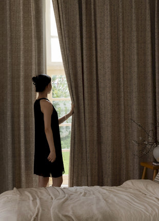 a woman standing in front of a window in a bedroom