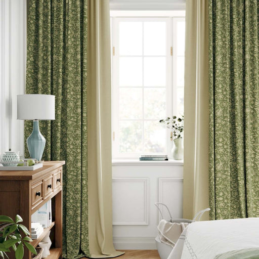 a bedroom with green curtains and a white bed
