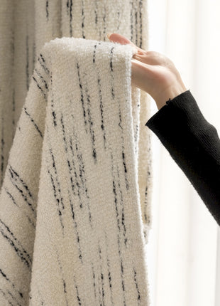 a person holding a curtain with a black and white pattern