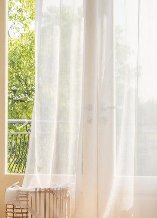 a window with a white curtain and a white radiator