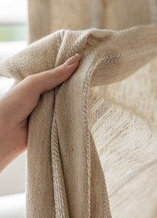 a hand is holding a blanket over a window