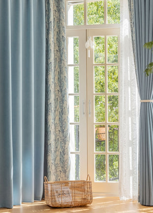a living room with blue curtains and a basket on the floor