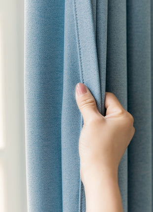 a person's hand is holding the curtain in front of a window