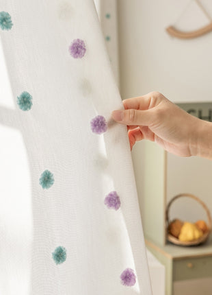 a person is holding a curtain with flowers on it