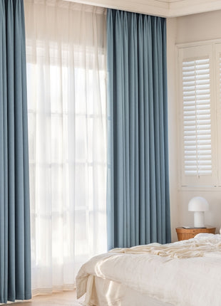 a bedroom with a white bed and blue curtains