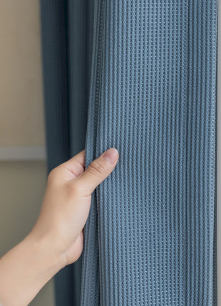 a person is opening a curtain with their hand