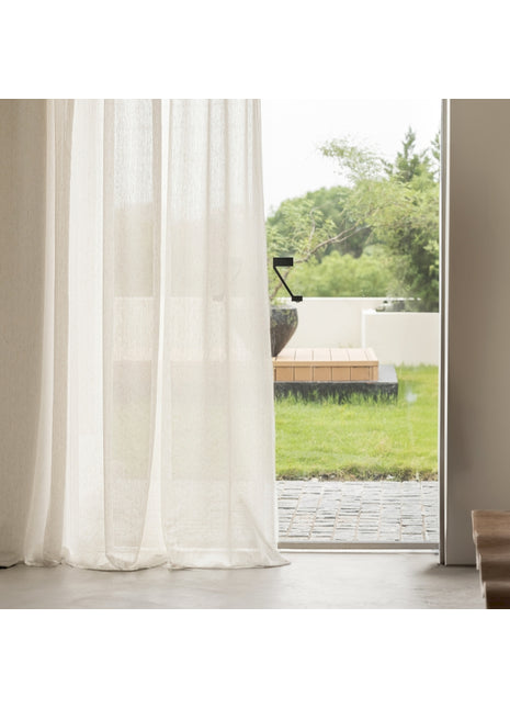 a window with a white curtain and a wooden bench