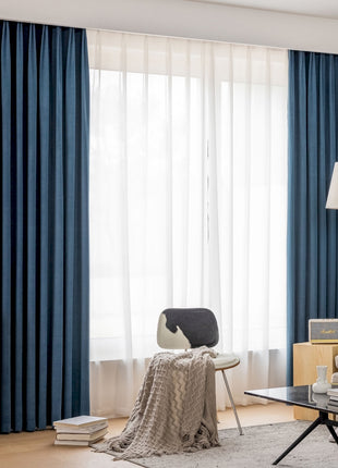 a living room filled with furniture and a window covered in blue curtains