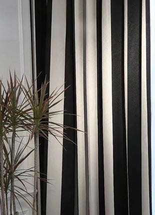 a black and white striped curtain next to a potted plant