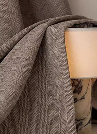 a close-up view of a brown fabric with a herringbone pattern, partially draped over a lamp shade.