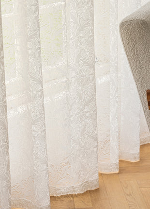 a chair sitting in front of a window with white curtains