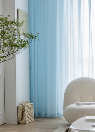 a living room with a white chair and a blue curtain