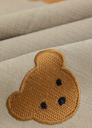a brown teddy bear embroidered on a tan fabric